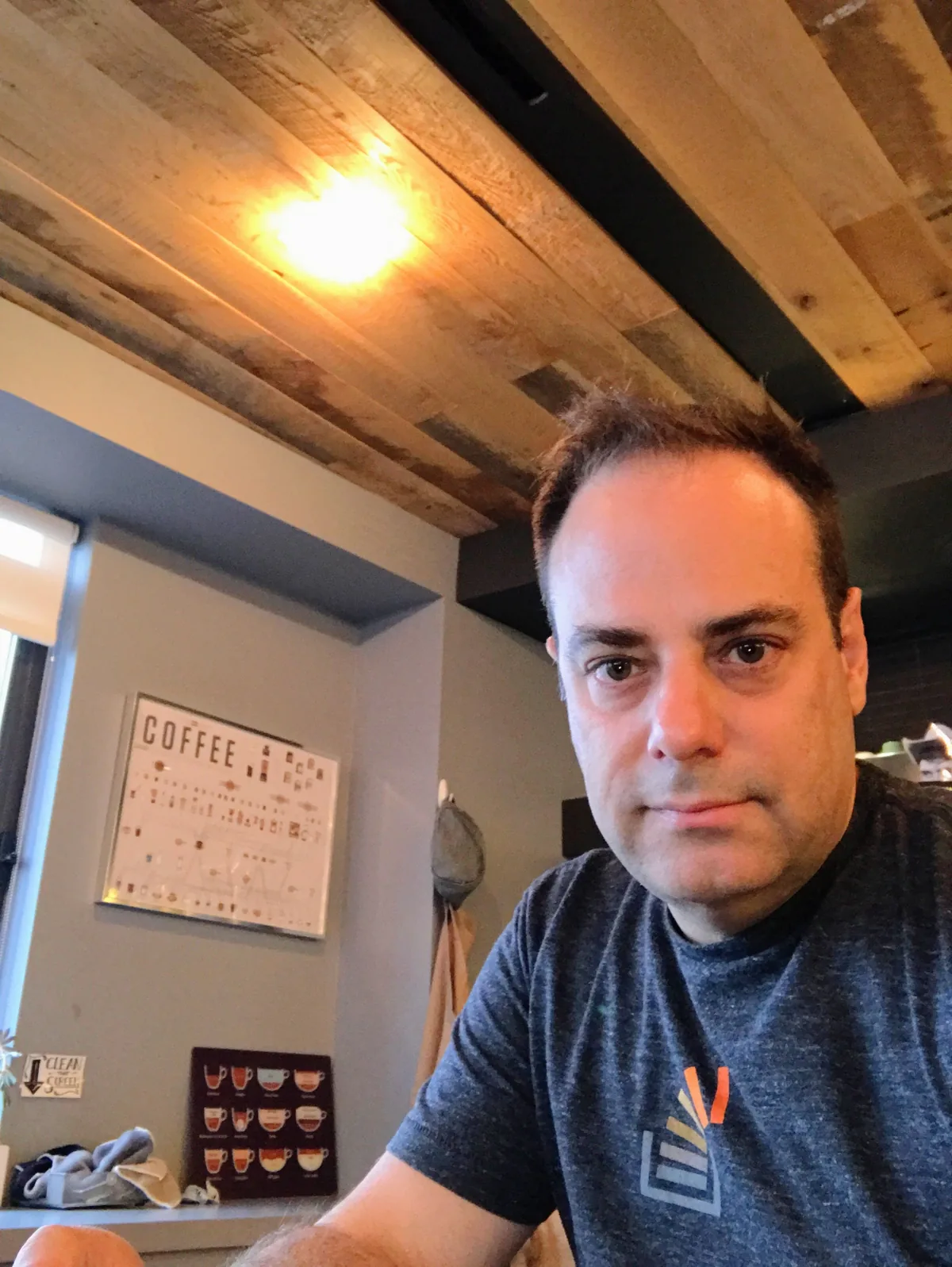 Joel Spolsky, seated in a coffee shop with a reclaimed-wood ceiling above him, looking straight at the camera.